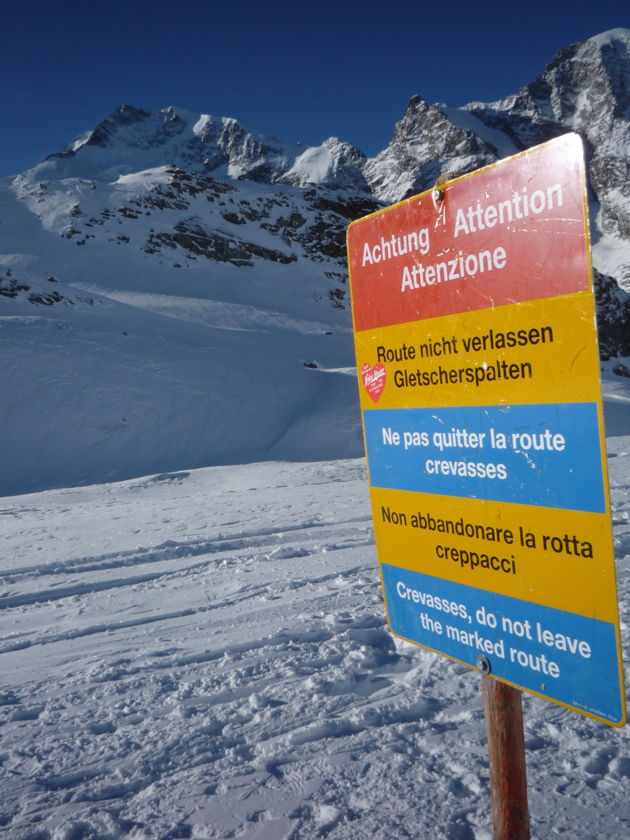 Piz Bernina (4049 m) a Morteratsch-gleccserről; tábla figyelmeztet a gleccserhasadékokra a kijelölt út elhagyása esetén