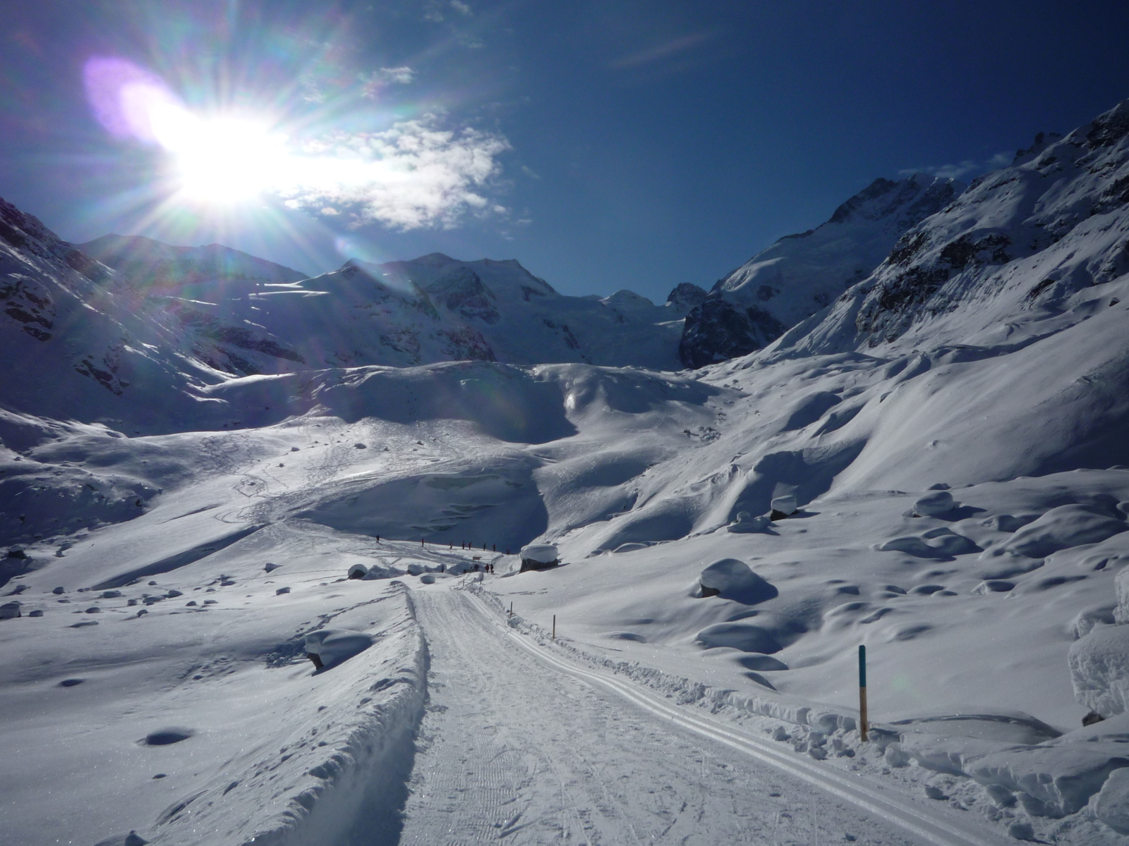 A Morteratsch-gleccser vége a völgy alján (háttérben a Bernina-hegység), innentől alig lejt tovább a túraútvonal a vasútállomásig