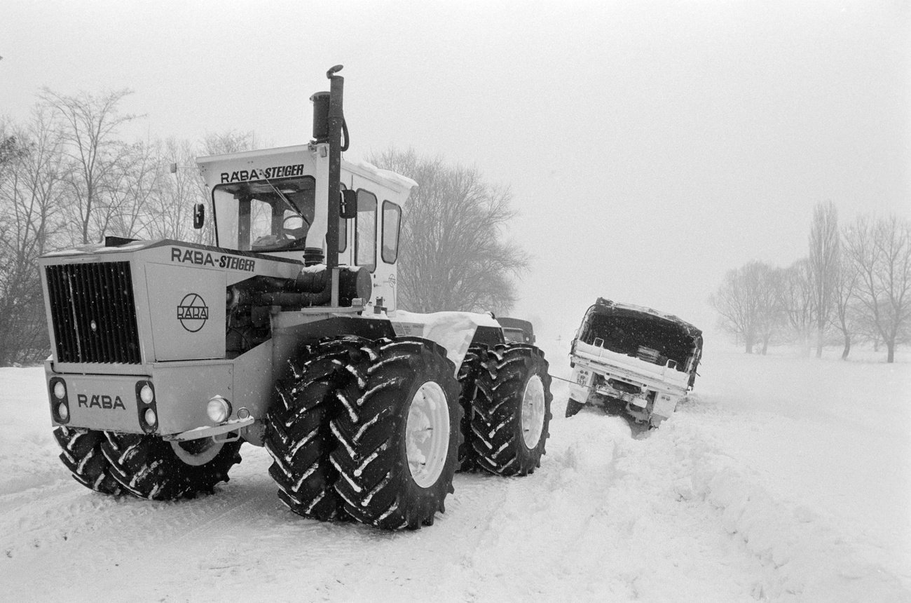 Lébénymiklós, 1987. január 17. Egy mezőgazdasági vontató húzza ki az útról lecsúszott mentésre induló honvédségi teherautót. Fotó: MTI