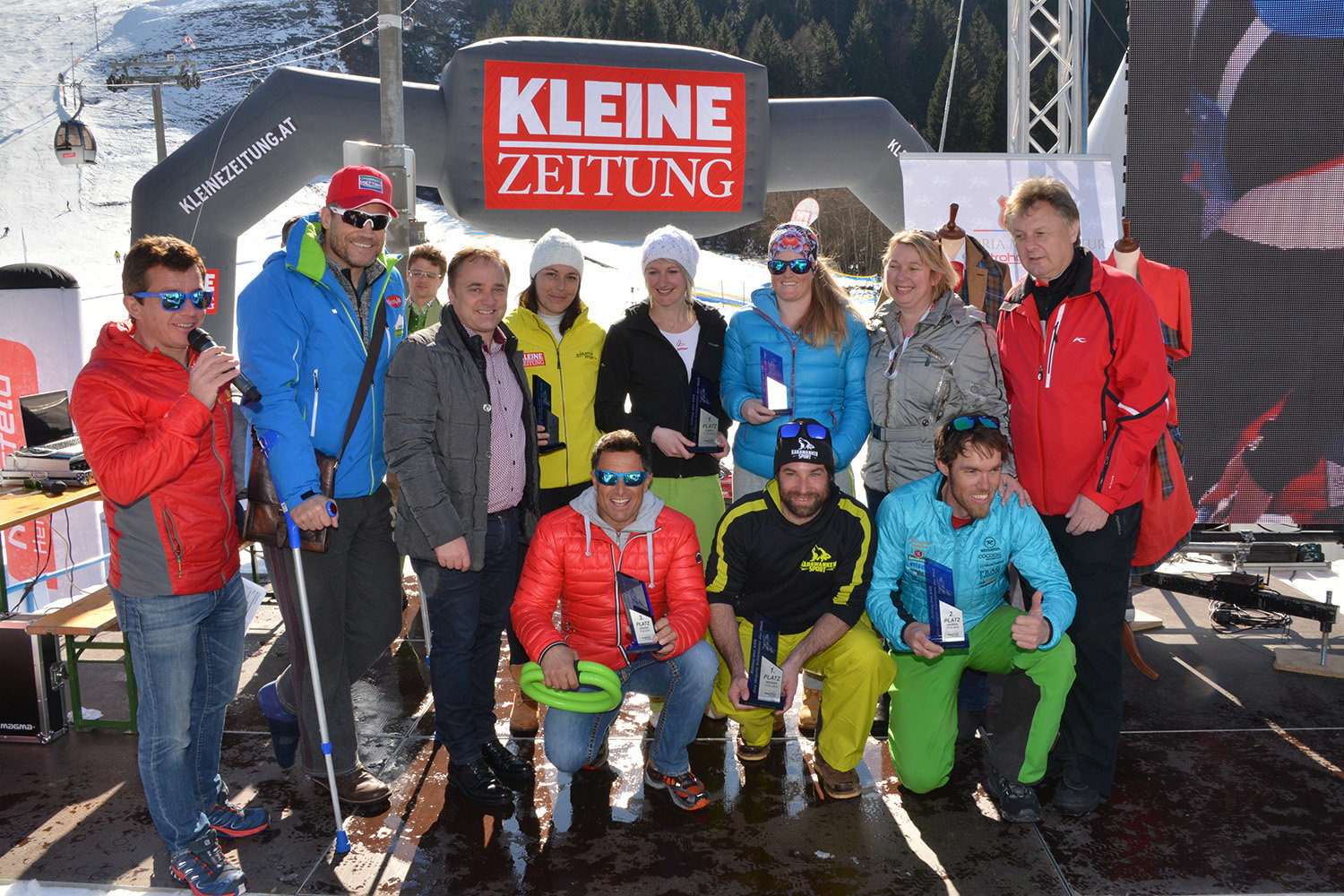 A 6. Schlag das Ass - A világ leghosszabb sífutóversenye büszke győztesei trófeáikkal és a sérült házigazdával Armin Assingerrel