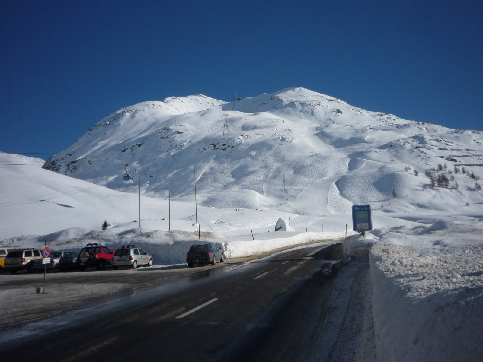 Lagalb (2959 m) a főút melletti felvonó  alsó állomásától; a főút menti tábla jelzi, hogy a Bernina-hágó (2330 m) járható (felfelé végig kétméteres hófal szegélyezi az utat)
