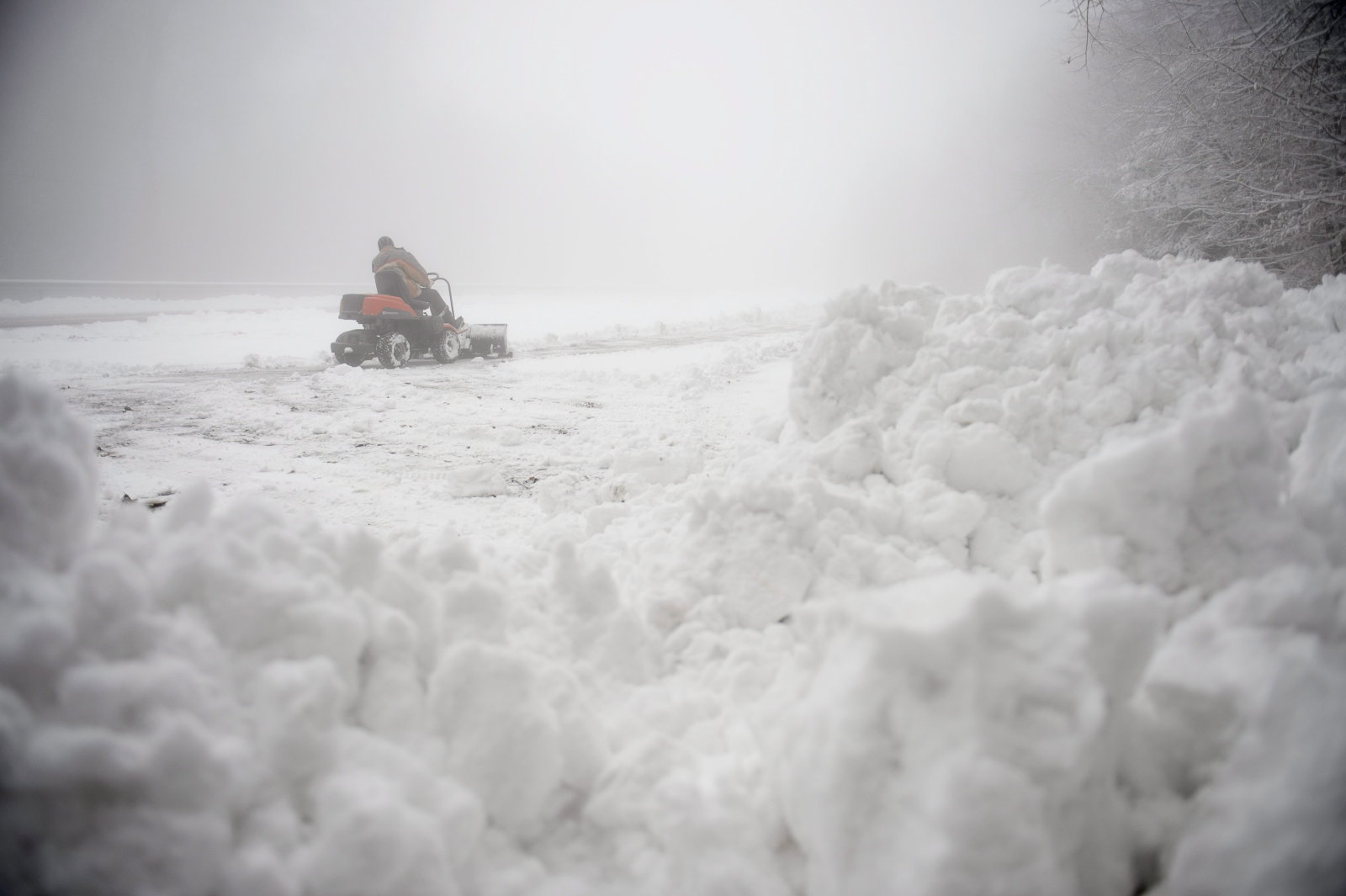 Egy férfi tolólapos traktorral takarítja el a havat egy parkolóból Kékestetőn 2014. november 25-én. MTI Fotó: Komka Péter