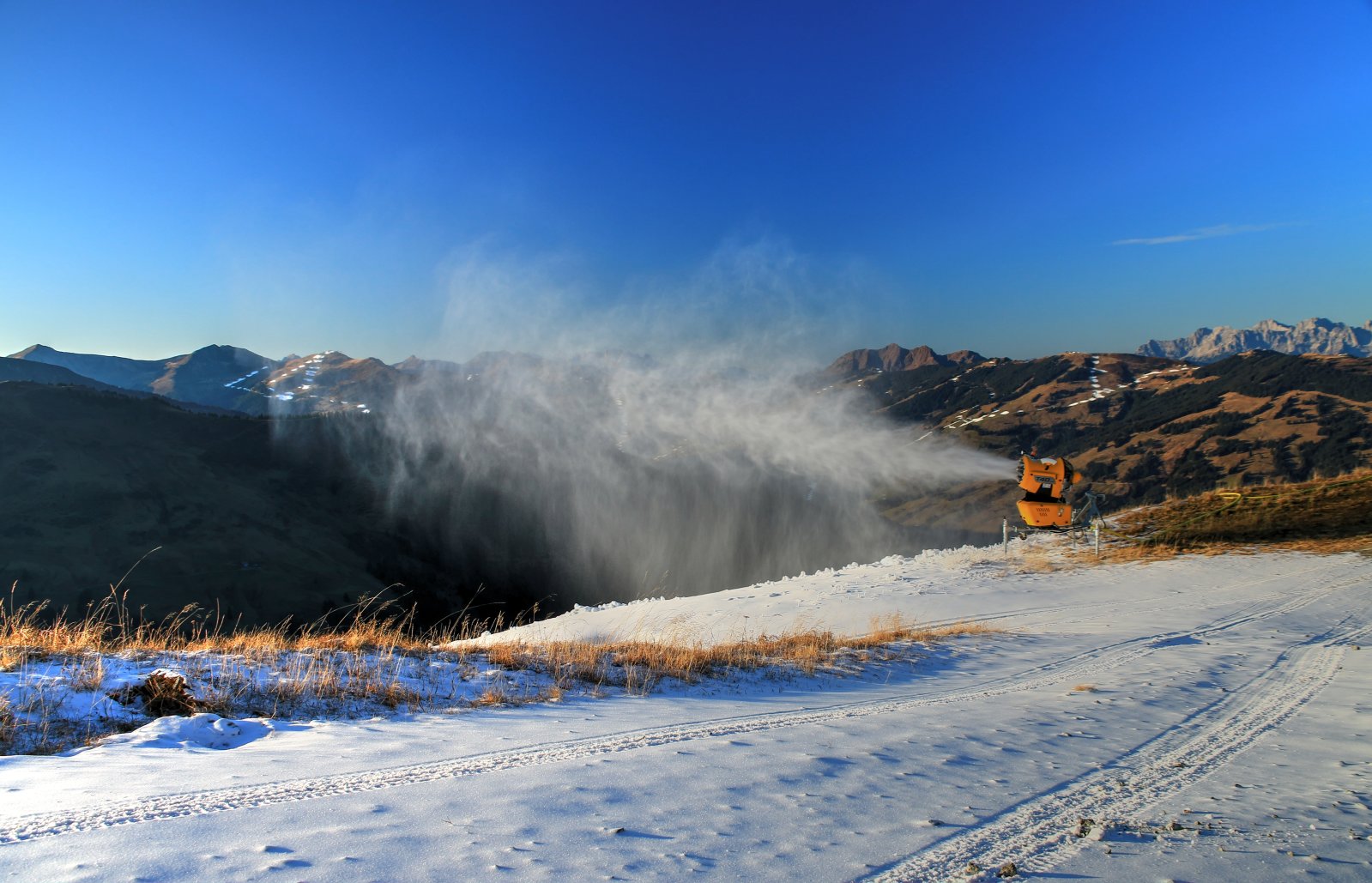 Üzemelő hóágyú, háttérben Saalbach sípályái