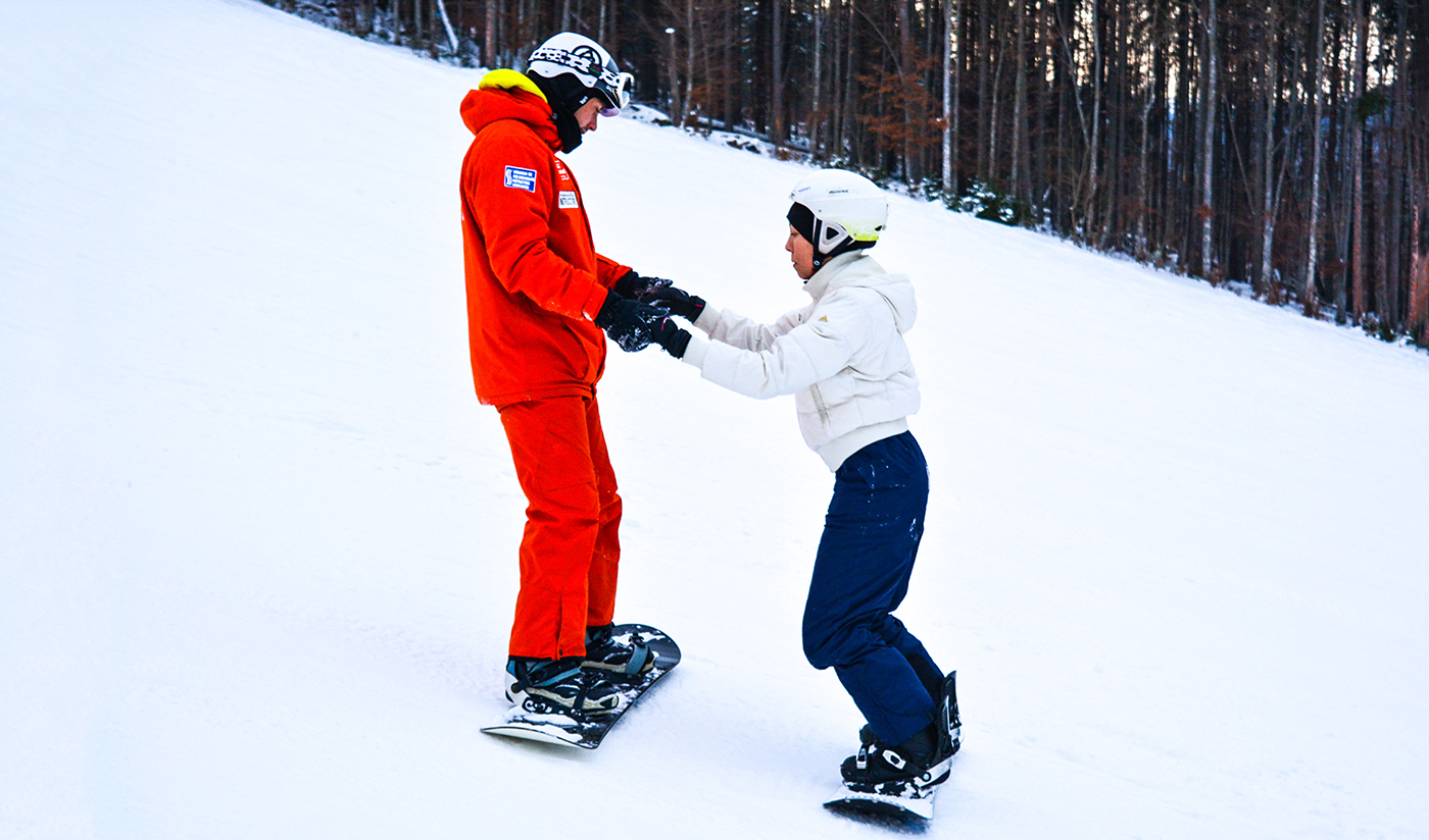 A snowboardoktató segít elsajátítani a helyes technikát A snowboardoktató segít elsajátítani a helyes technikát