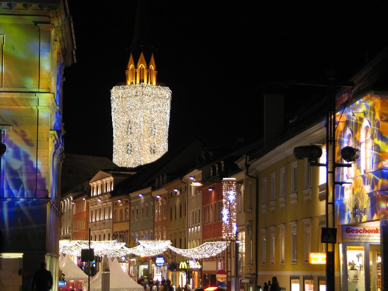 A díszkivilágításba öltöztetett templomtorony ezüstösen lobogó gyertyaként világítja meg a karácsonyi vásárt.